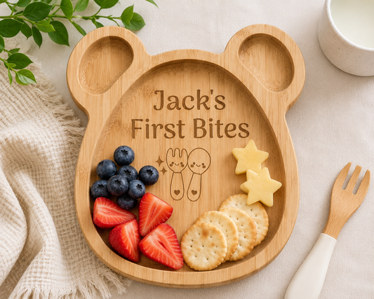 Wooden plate shaped like a bear with 'Jack's First Bites' engraving, containing fruits and cookies.