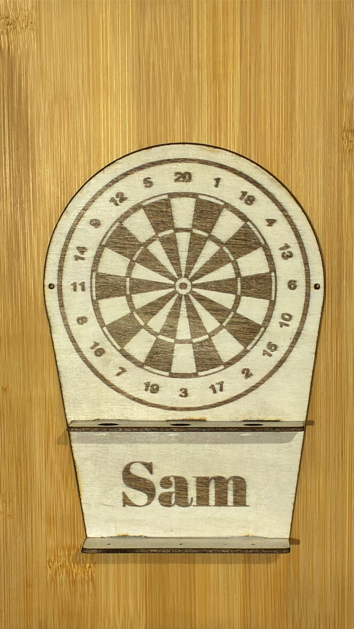 Wooden dart holder with 'Sam' engraved on a wooden background