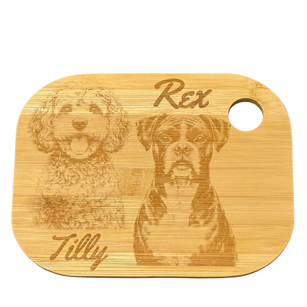 Bamboo chopping board with engraved portraits of two dogs and their names on a white background