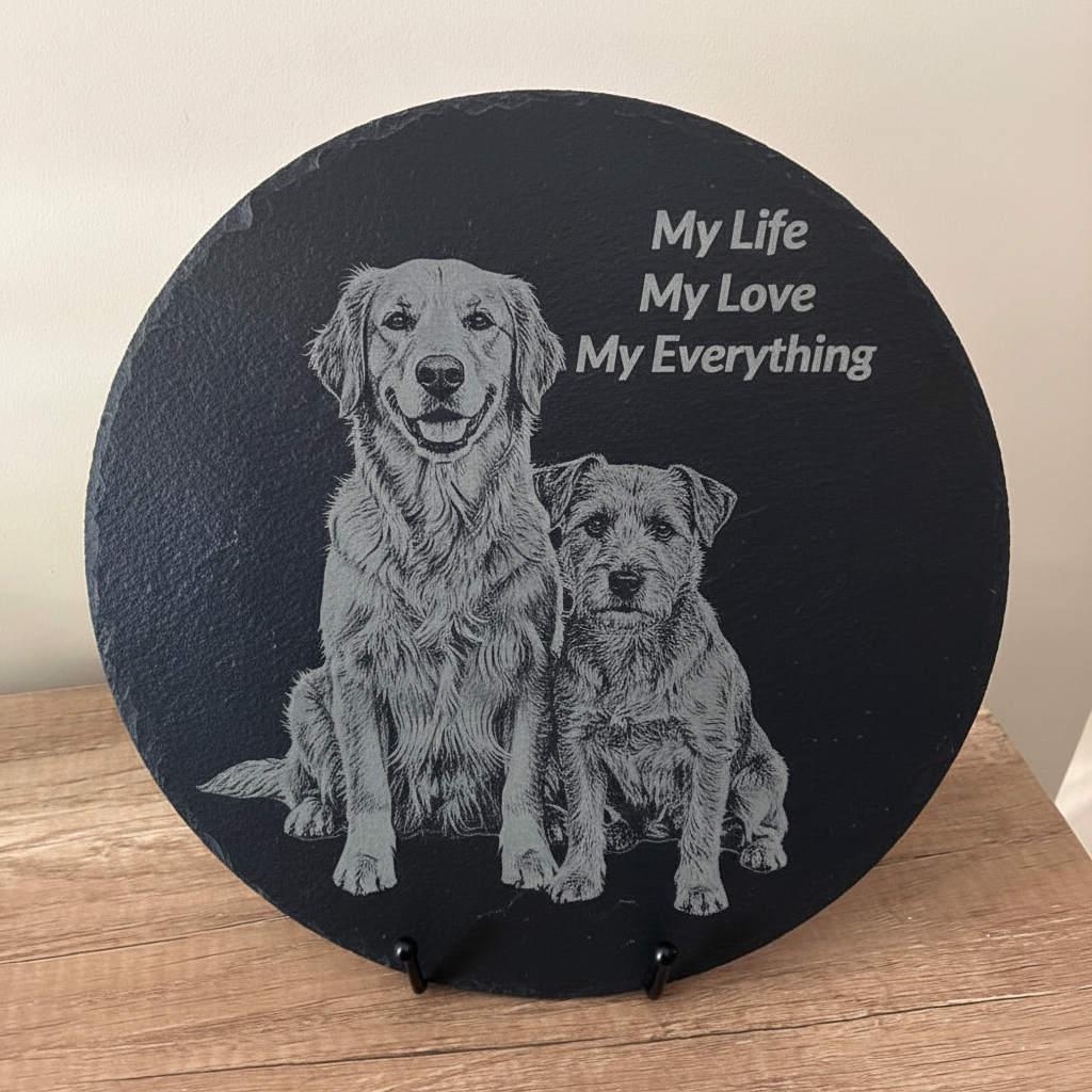 Round black slate with engraved images of two dogs and text 'My Life, My Love, My Everything' on a wooden surface.