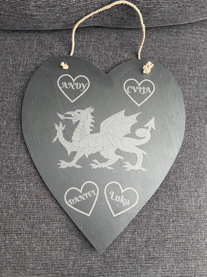 Heart-shaped slate plaque with engraved Welsh dragon design and names engraved in hearts on a grey fabric background