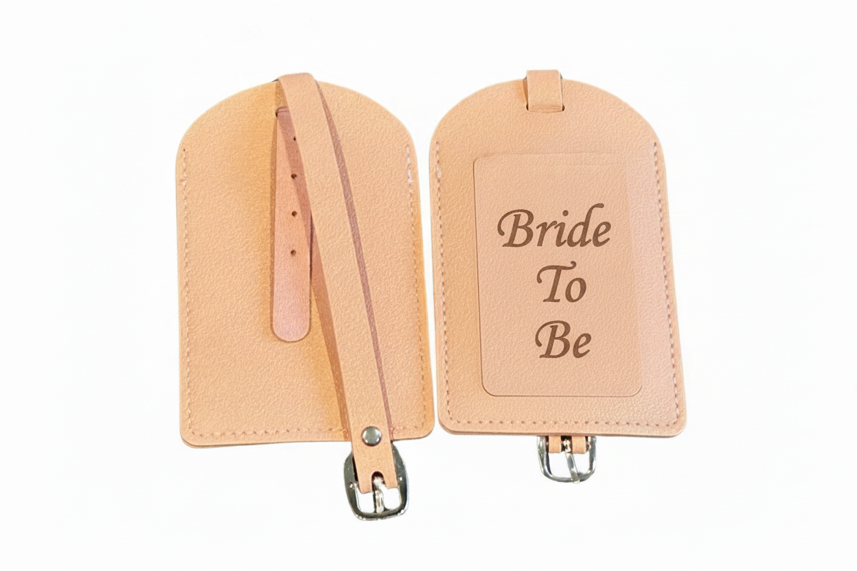 Two pink-colored luggage tags with Bride to Be engraved with straps on a white background