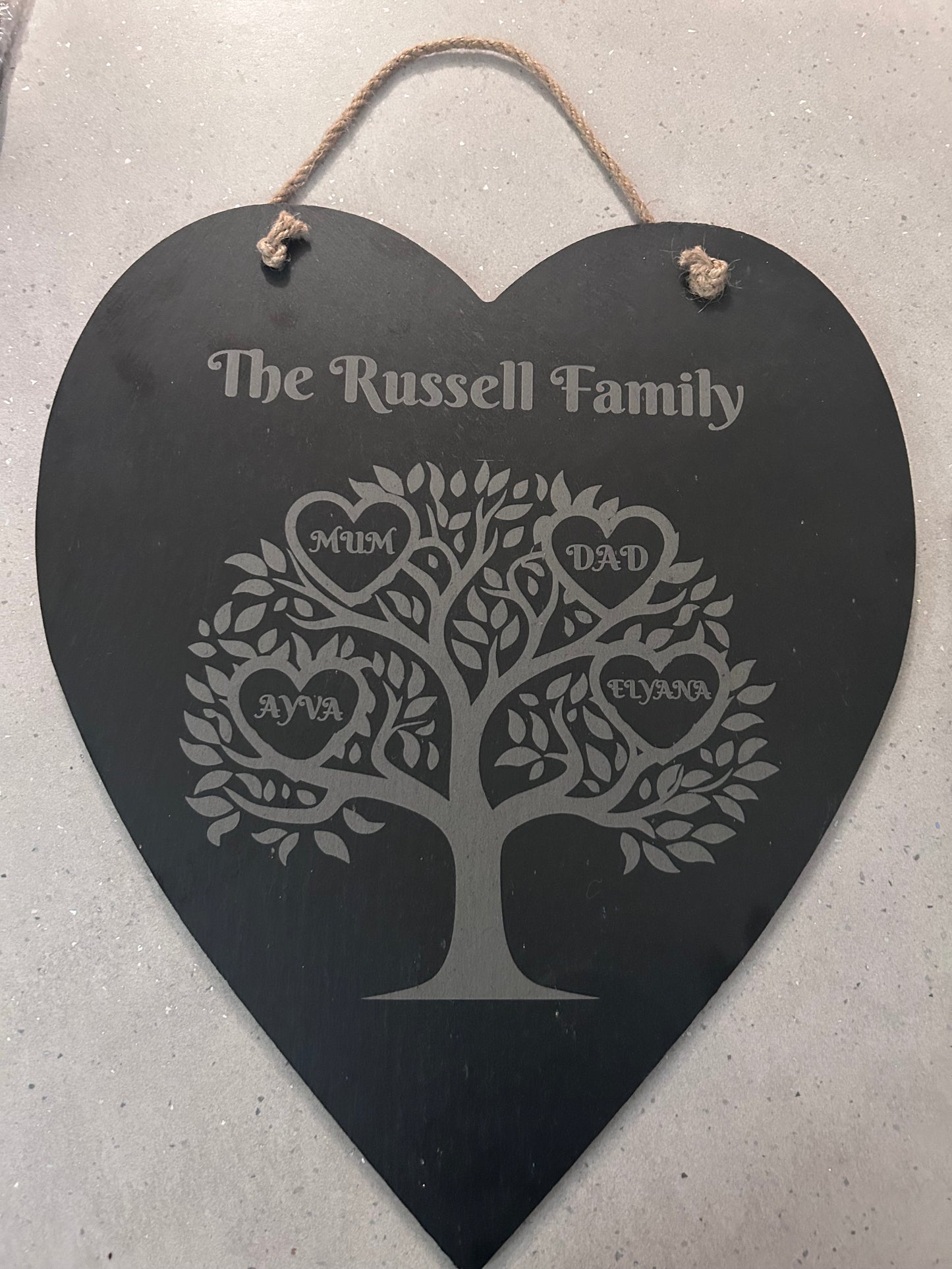 Heart-shaped family tree plaque with engraved names hanging on a wall 