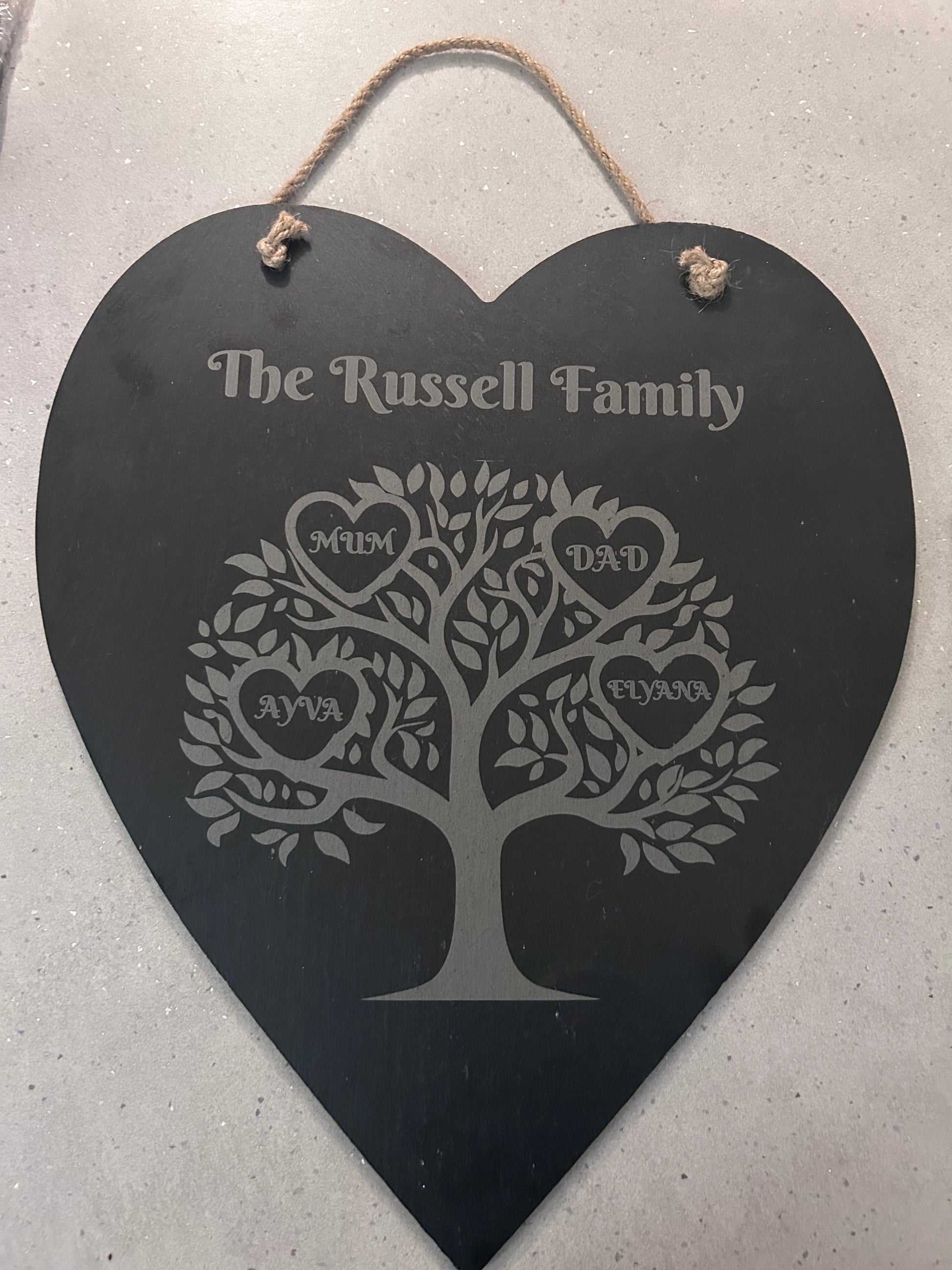 Heart-shaped family tree plaque with engraved names hanging on a wall 
