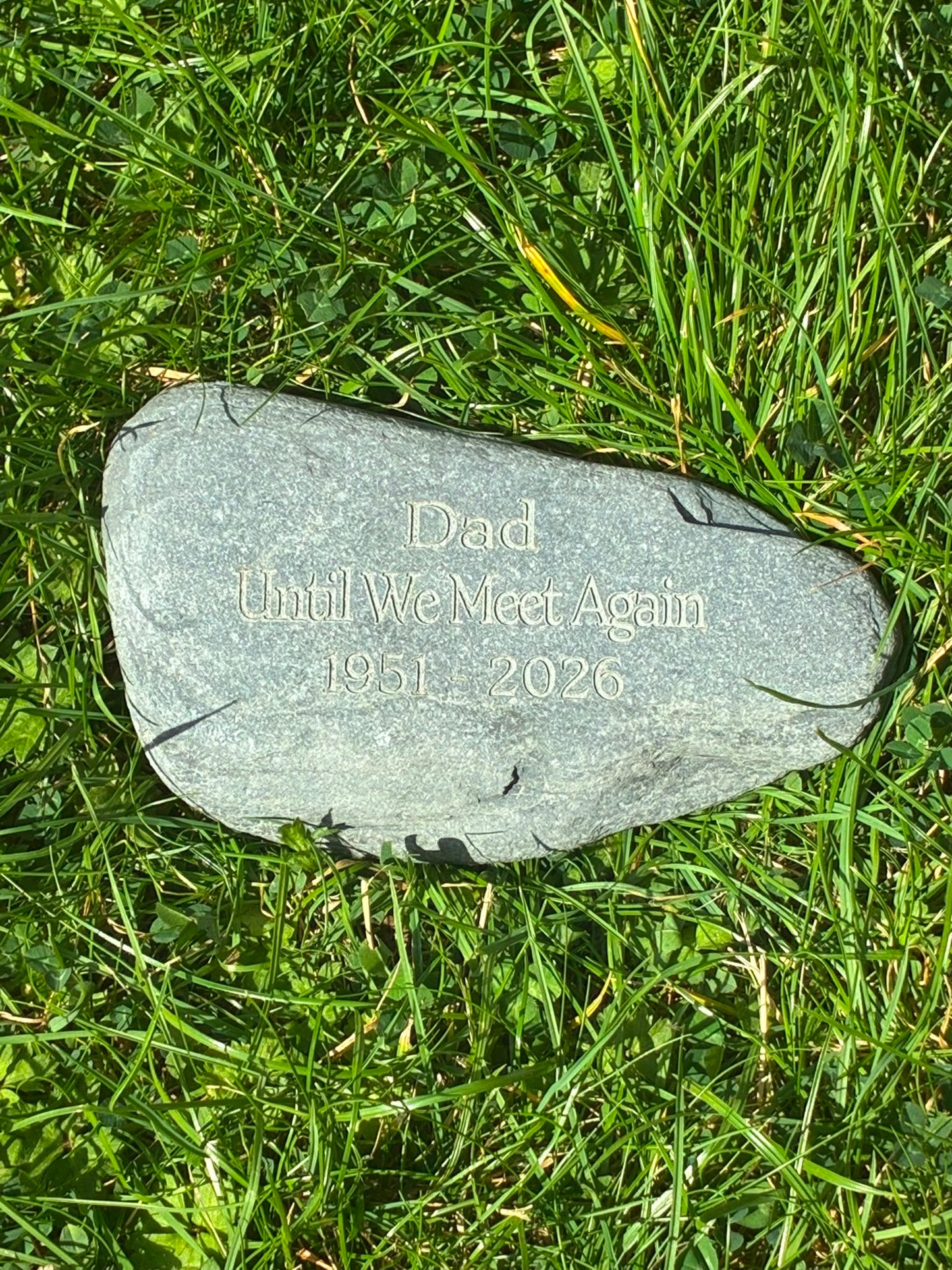 Natural grey memorial stone engraved with a personalised remembrance message for Dad, displayed on grass