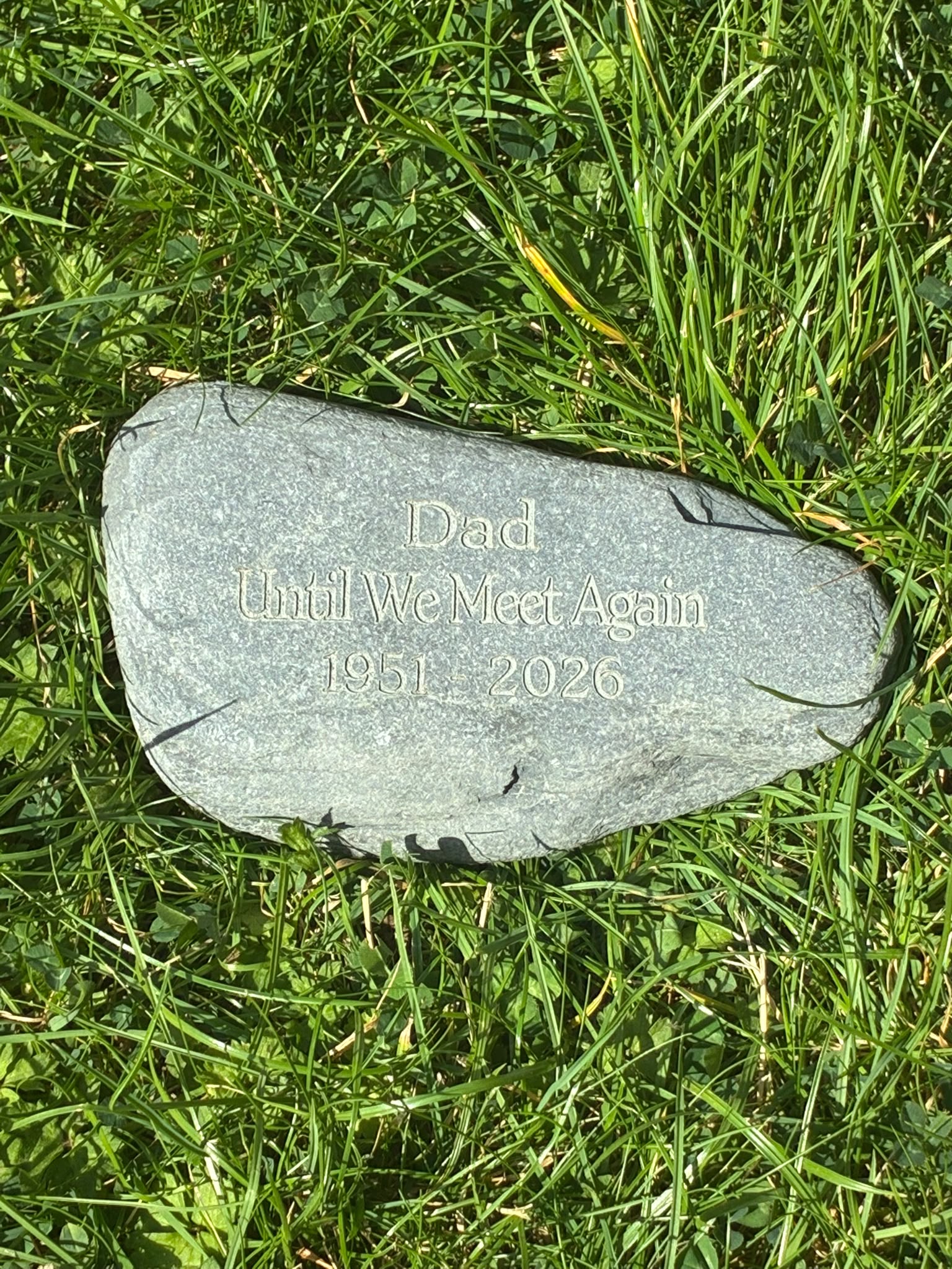 Natural grey memorial stone engraved with a personalised remembrance message for Dad, displayed on grass
