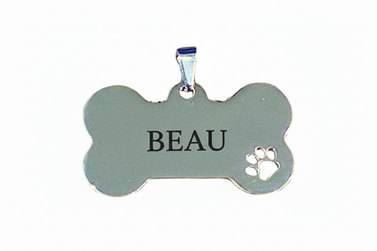 Dog bone-shaped pendant with paw print cutout on a white background
